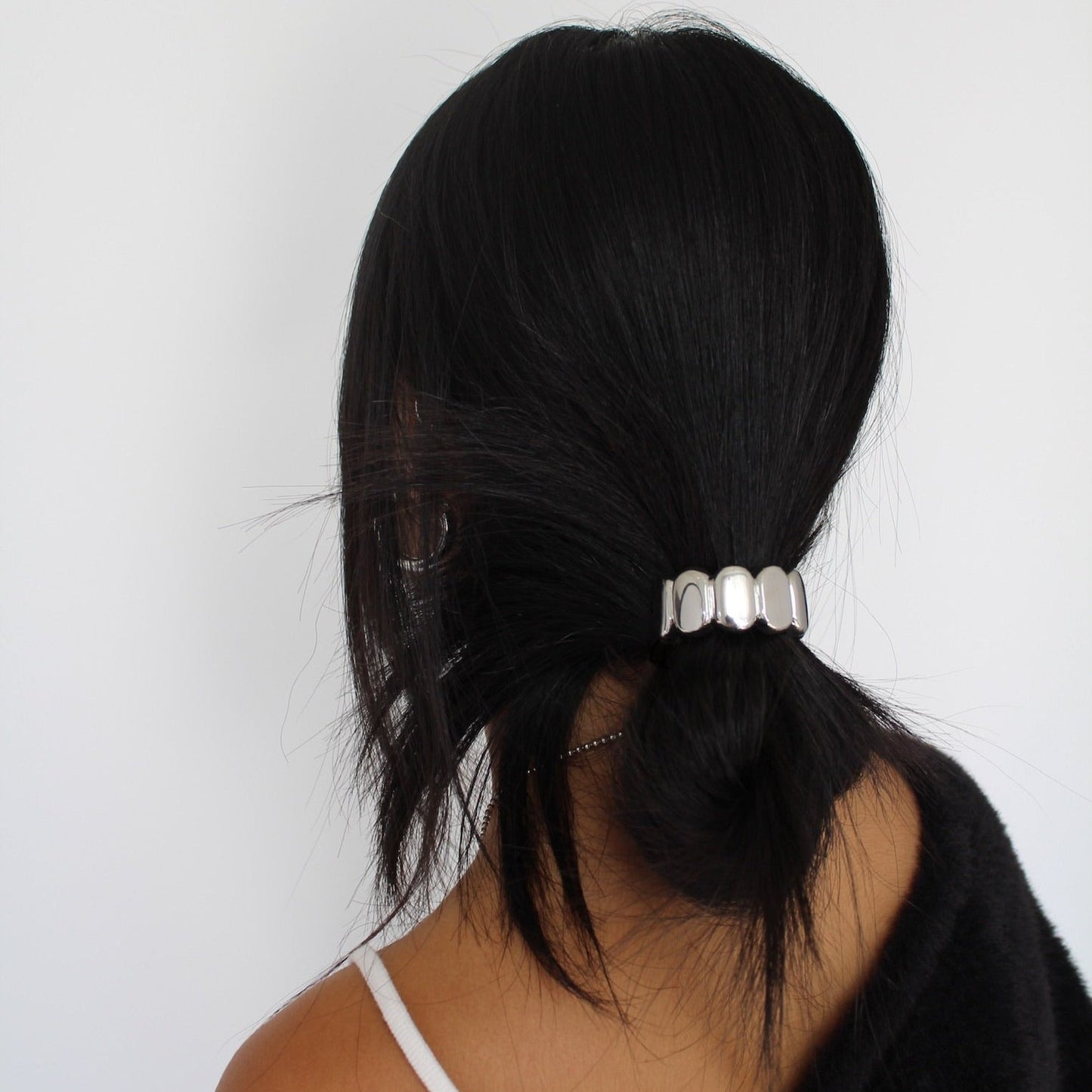 Women with black hair wearing a silver ponytail cuff