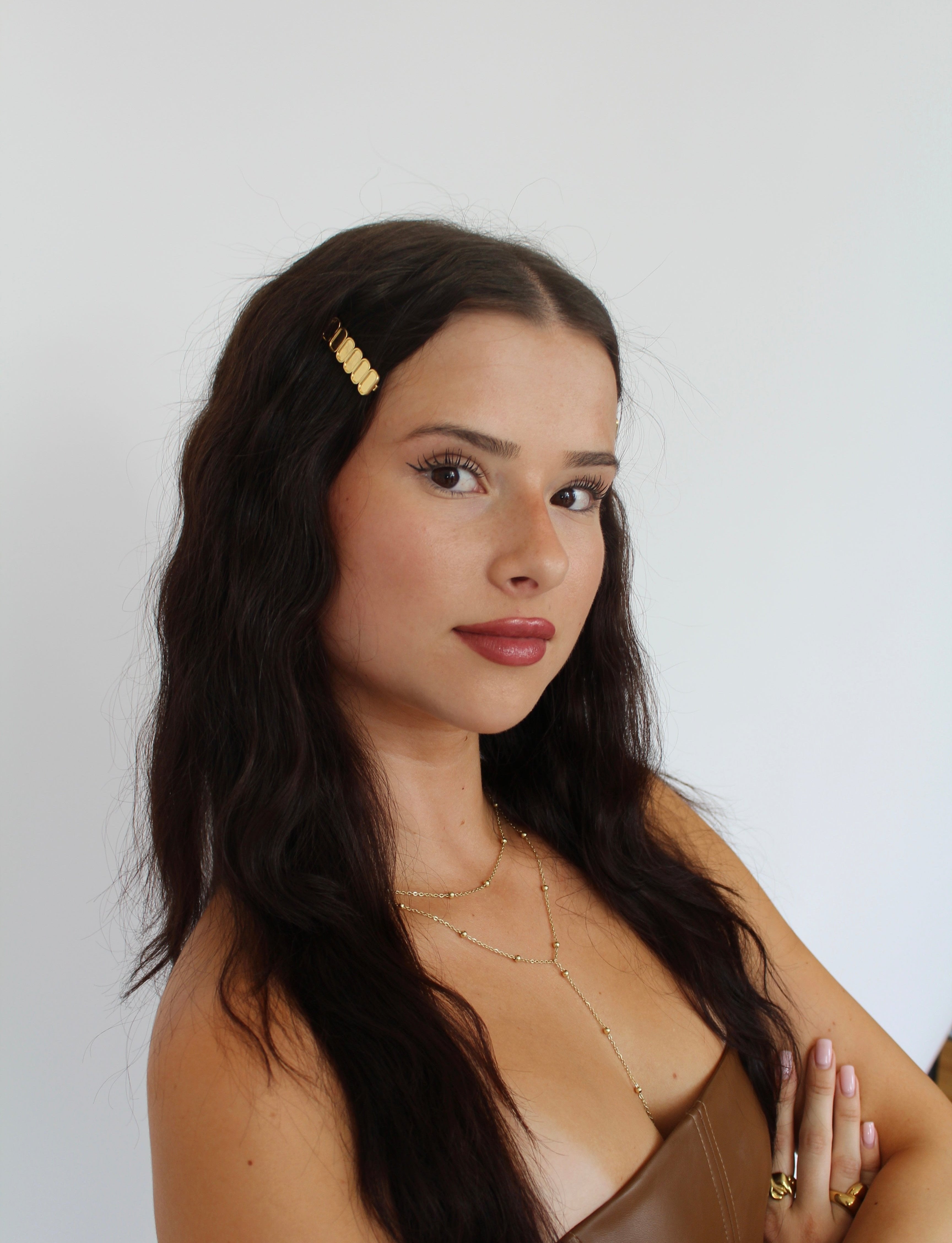 Women with brown hair wearing gold hairpins and brown top