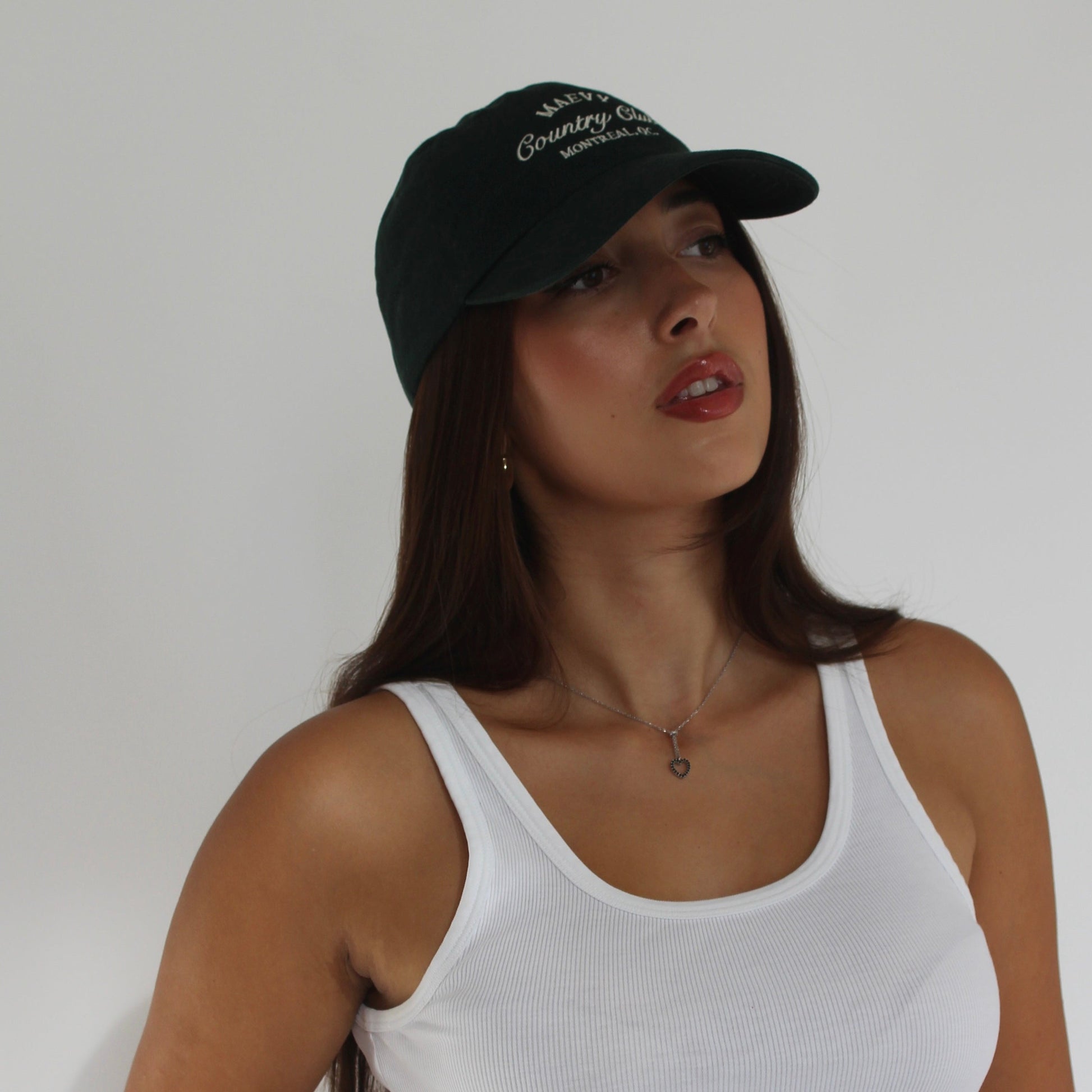 Women with long brown hair wearing green baseball cap and white tank top