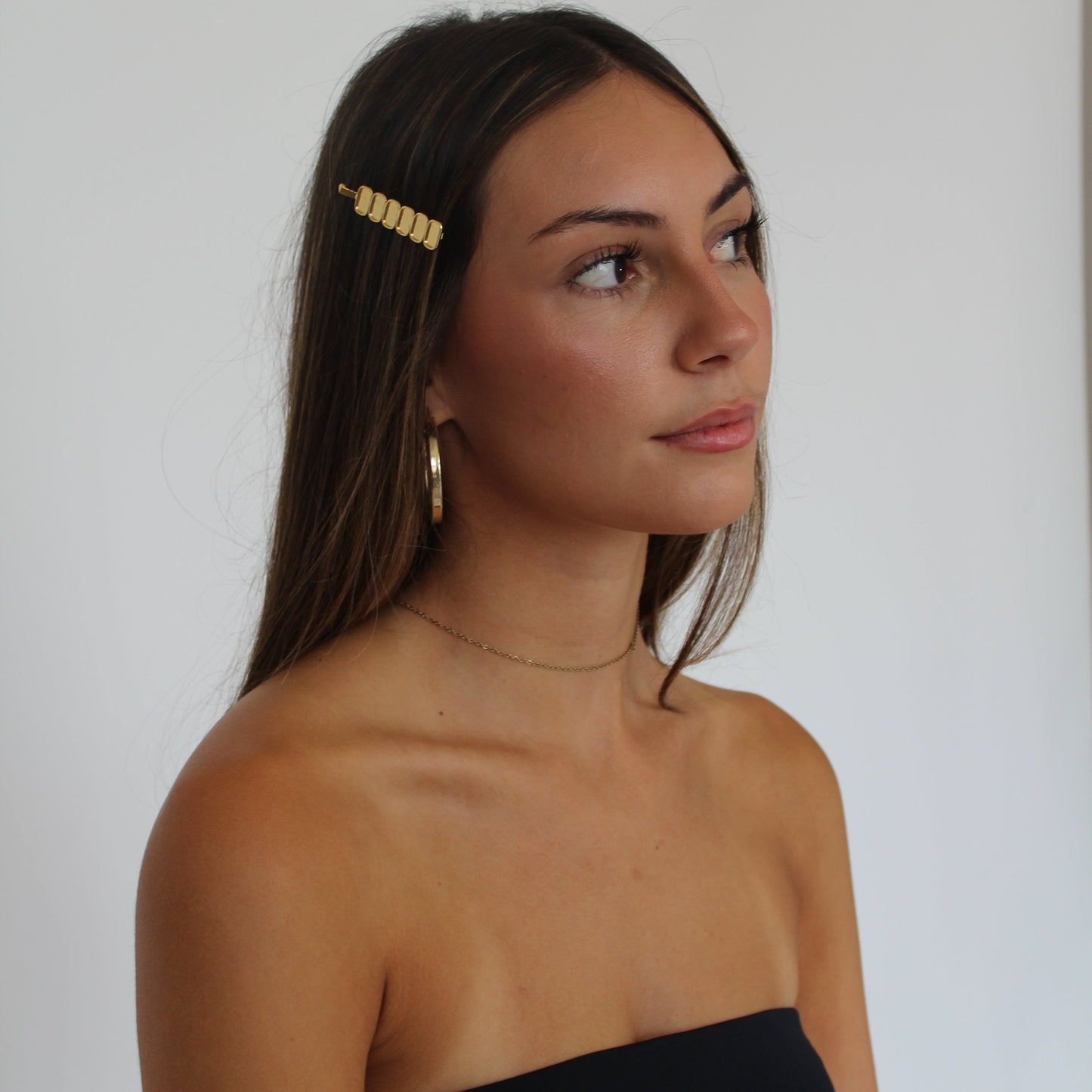 Women with brown hair wearing gold hairpin and gold earrings