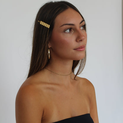 Women with brown hair wearing gold hairpin and gold earrings