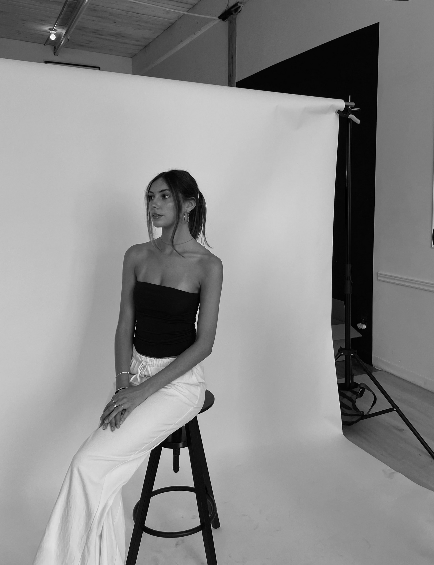 Model sitting on bench with white backdrop at photoshoot 