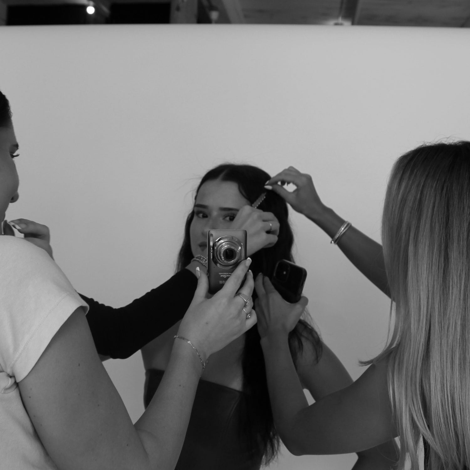 Model doing a photoshoot, getting her hair styled with gold hairpins