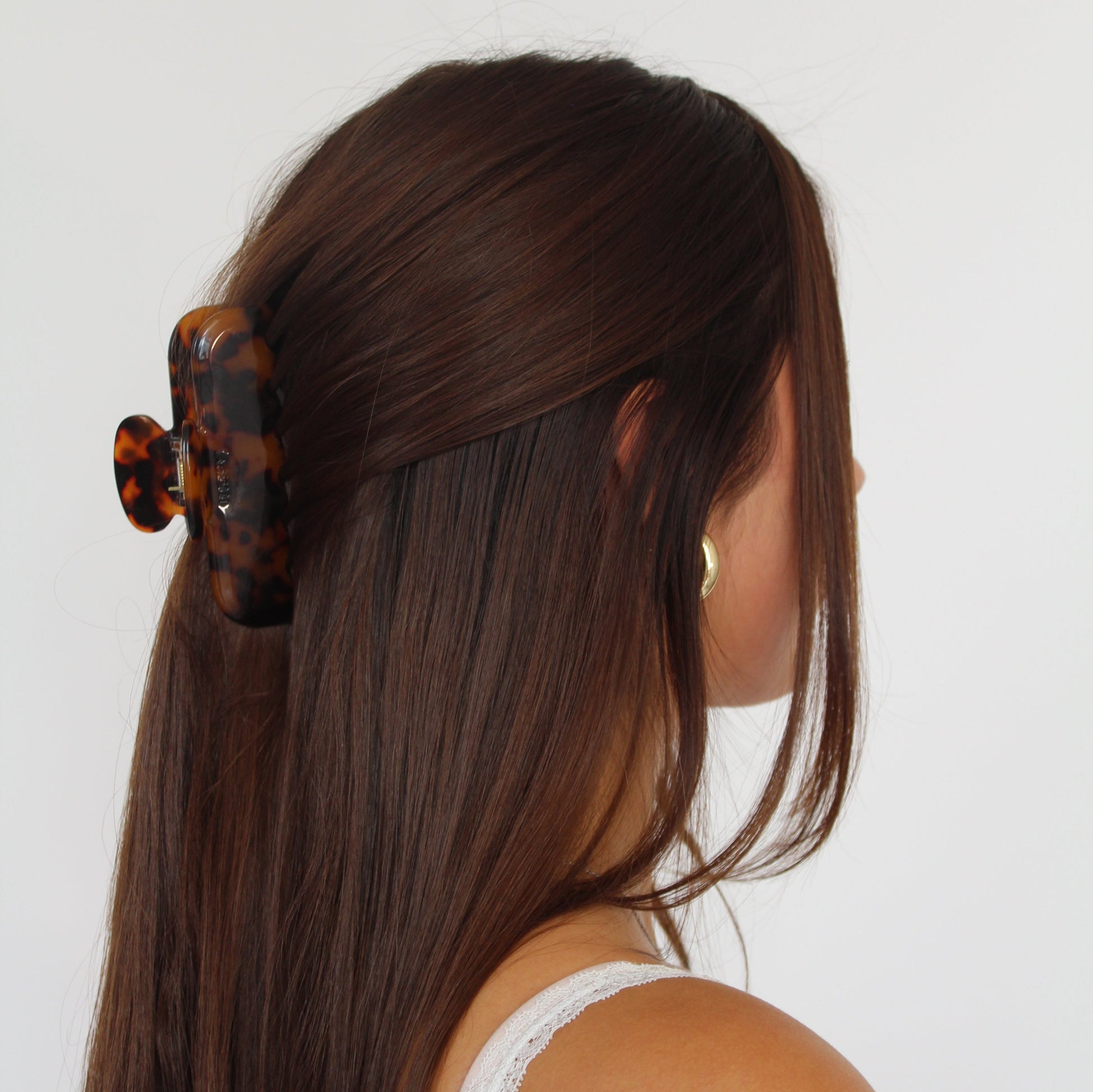 Women with long brown hair wearing black and brown tortoise claw clip